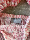 Brand tag and clothing label on the girls pink tie dye smocked top.