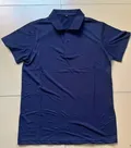 Men's navy polo shirt hanging on wall showing M size tag and back construction detail for bulk buyers