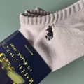 Close-up of men's beige no show sock ribbed cuff and branded packaging for bulk resale
