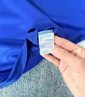 Fabric care label showing 100% polyester composition on men's polo shirt wholesale stock