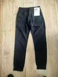 Flat lay of men's black cuffed casual pants with factory hang tag for wholesale buyers