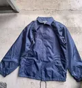 Navy blue men's coaches jacket flat lay showing five snap button placket and side slash pockets for wholesale buyers