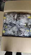 Open cardboard box showing bulk women's black and white plaid shacket inventory in original poly-bag packaging for wholesale