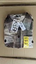 Single women's plaid shacket folded in box with S/P yellow size sticker and retail hang tag showing original order stock