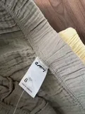 Care label showing 100% cotton on women's pull-on shorts with original retail tag attached for bulk inventory