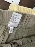 Women's olive cotton shorts waistband detail showing 11/25 size label and gathered shirring construction for wholesale buyers