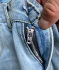 Close-up of zipper and waistband on women's rigid denim curved wide-leg jeans for boutique resale