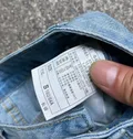 Fabric care label showing 85% cotton composition on light blue denim wholesale stock for distributors