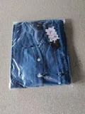 Close-up of premium vertical tailored pin-tuck pleats and glossy pearlized button down closure on denim shirt jacket